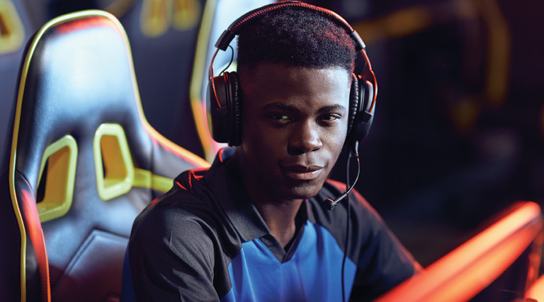 Student wearing headphones sitting in front of desktop computer playing esports