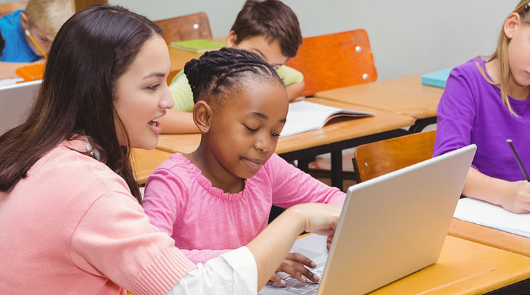Teacher using laptop with student